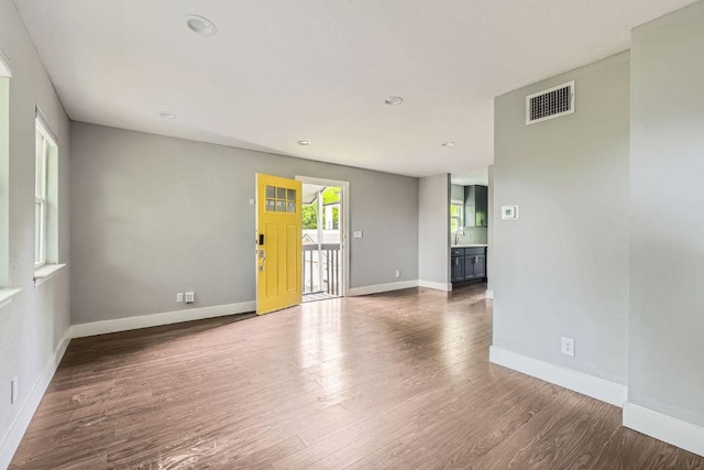 spare room with wood finished floors, visible vents, and baseboards