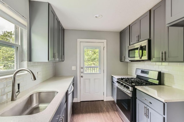 kitchen featuring plenty of natural light, dark wood finished floors, stainless steel appliances, and a sink