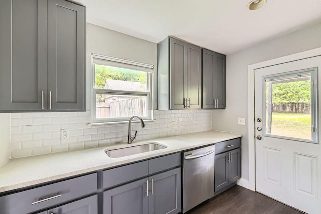 kitchen featuring plenty of natural light, stainless steel dishwasher, gray cabinets, and a sink