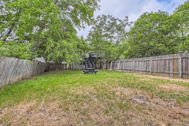 view of yard with a fenced backyard, stairs, and a deck