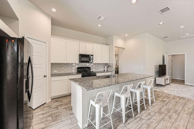 11509 Brindle Ct, Manor, TX 78653 - kitchen featuring black appliances, a sink, wood tiled floors, white cabinets, and recessed lighting