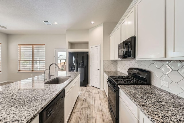 11509 Brindle Ct, Manor, TX 78653 - kitchen with black appliances, a sink, wood finish floors, white cabinets, and backsplash