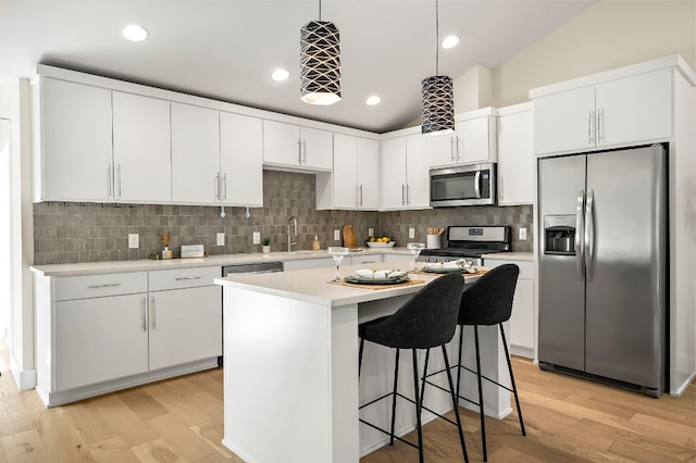 4709 Bandera Rd, Austin, TX 78721 - kitchen with stainless steel appliances, light countertops, white cabinets, light wood-style flooring, and a breakfast bar