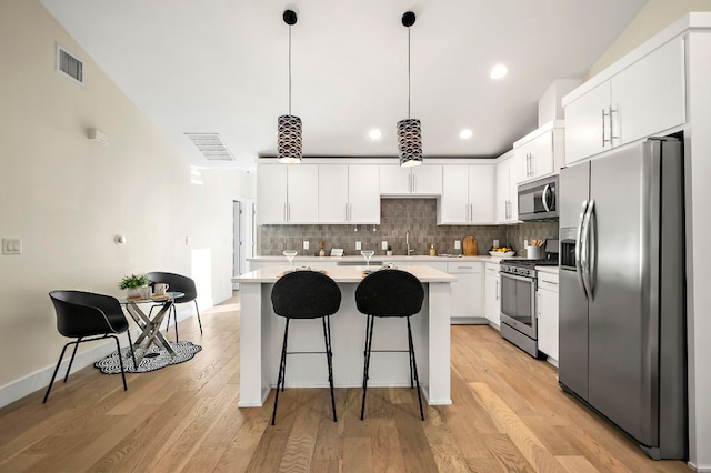 4709 Bandera Rd, Austin, TX 78721 - kitchen featuring stainless steel appliances, light countertops, backsplash, white cabinetry, and a breakfast bar