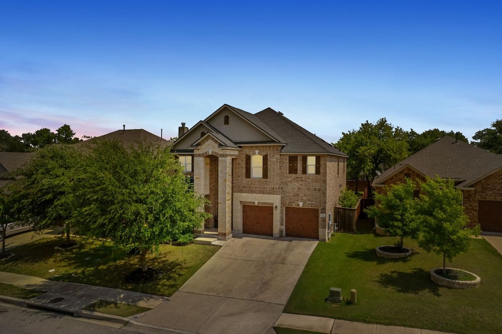 1724 Bovina Dr, Leander, TX 78641 - view of front of home featuring driveway, an attached garage, a lawn, and brick siding