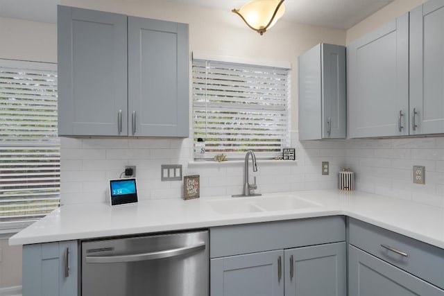 17320 Manish Dr, Pflugerville, TX 78660 - kitchen with stainless steel dishwasher, a sink, gray cabinets, and light countertops
