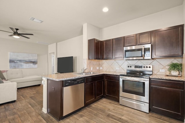 604 Nueces River Trl, Hutto, TX 78634 - kitchen featuring visible vents, dark brown cabinetry, a peninsula, appliances with stainless steel finishes, and open floor plan