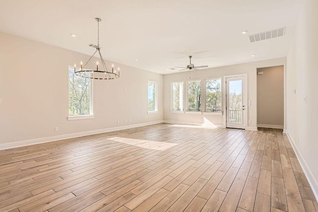 interior space featuring light wood-type flooring, visible vents, baseboards, and ceiling fan with notable chandelier