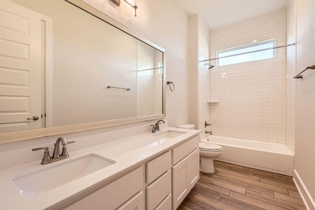 bathroom with double vanity, wood finished floors, toilet, and a sink