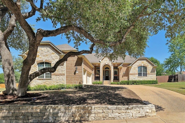 1900 Val Verde Dr, Austin, TX 78732 - view of front of home featuring driveway, fence, an attached garage, and stone siding