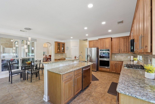 1900 Val Verde Dr, Austin, TX 78732 - kitchen with arched walkways, visible vents, appliances with stainless steel finishes, brown cabinetry, and ornamental molding