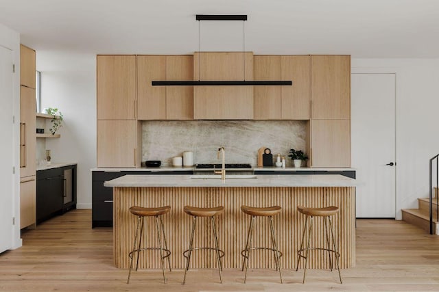 303 W Elizabeth St Unit A, Austin, TX 78704 - kitchen with light brown cabinetry, decorative backsplash, a breakfast bar, modern cabinets, and an island with sink