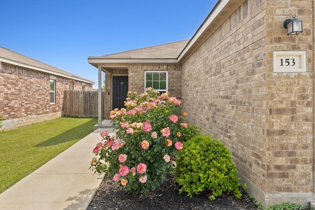 153 Proclamation Ave, Liberty Hill, TX 78642 - doorway to property featuring brick siding, fence, and a yard