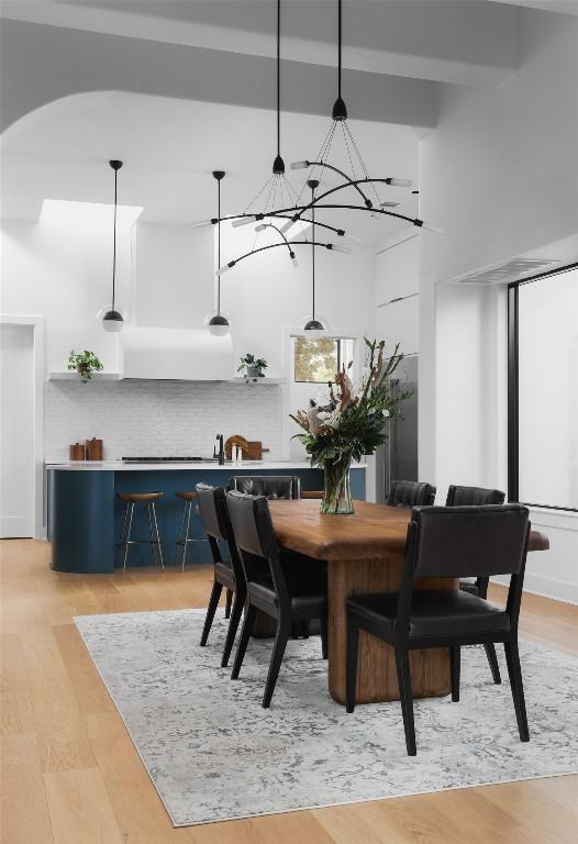 2709 Addison Ave, Austin, TX 78757 - dining area featuring a high ceiling, arched walkways, a notable chandelier, and light wood finished floors