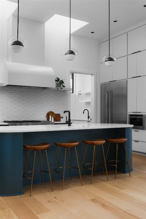 2709 Addison Ave, Austin, TX 78757 - kitchen with light wood-style floors, tasteful backsplash, pendant lighting, and modern cabinets