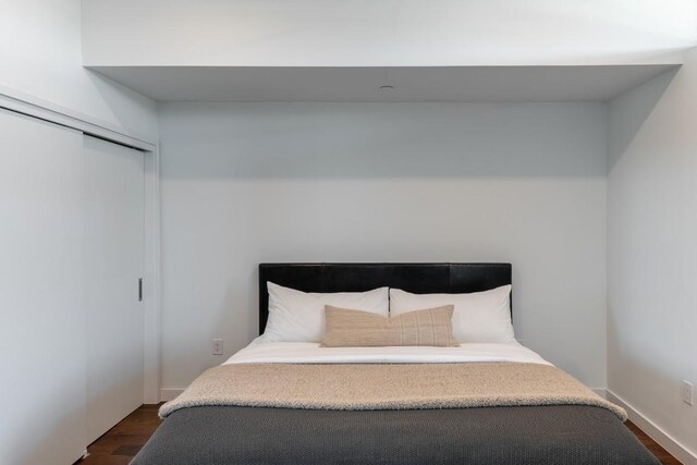 bedroom featuring baseboards, dark wood-style floors, and a closet
