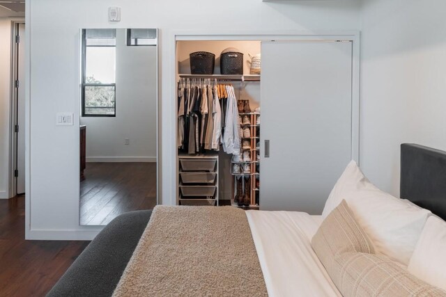 bedroom with wood finished floors, a closet, and baseboards