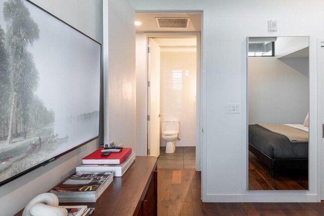 interior space with wood finished floors, visible vents, and toilet