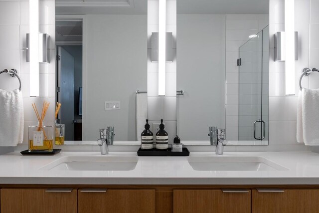 full bathroom featuring double vanity, a shower stall, and a sink