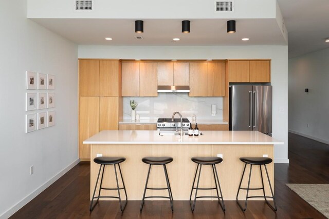 kitchen with under cabinet range hood, high quality fridge, a sink, and visible vents