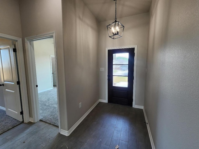 doorway with dark wood-type flooring, baseboards, and a chandelier