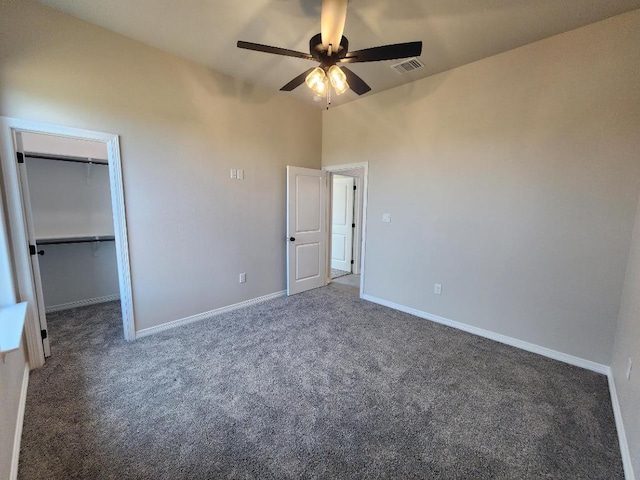 unfurnished bedroom featuring a walk in closet, ceiling fan, baseboards, carpet flooring, and visible vents