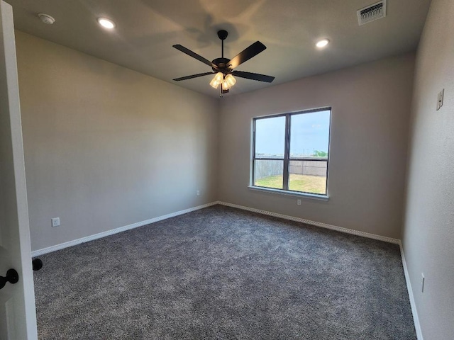 spare room with dark carpet, baseboards, a ceiling fan, and visible vents