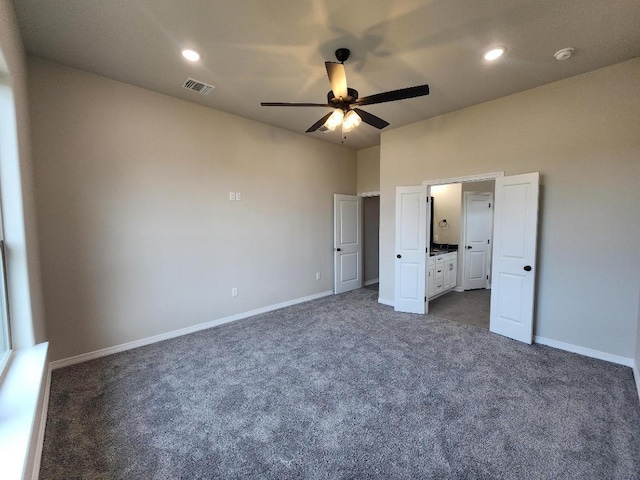 unfurnished bedroom with dark carpet, visible vents, a ceiling fan, ensuite bath, and baseboards