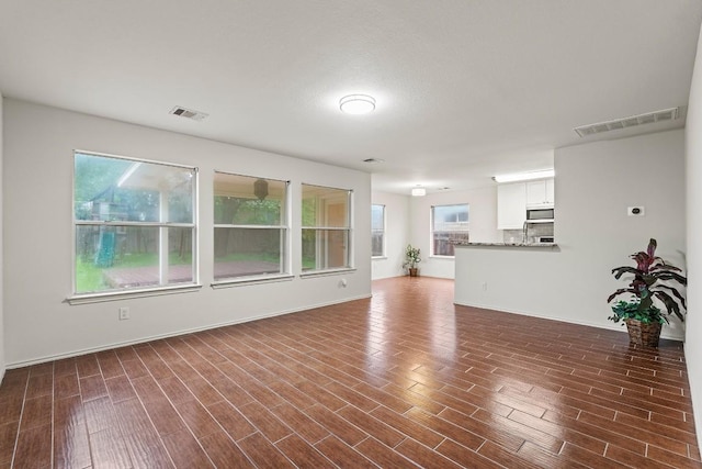 400 W Tudor House Rd, Pflugerville, TX 78660 - unfurnished living room featuring dark wood-style floors and baseboards