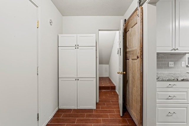 400 W Tudor House Rd, Pflugerville, TX 78660 - kitchen featuring white cabinetry, a barn door, backsplash, light stone countertops, and wood tiled floors