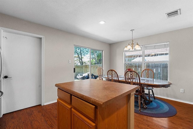 4302 Kings Canyon Dr, Taylor, TX 76574 - kitchen with a chandelier, a kitchen island, dark wood-style flooring, and visible vents