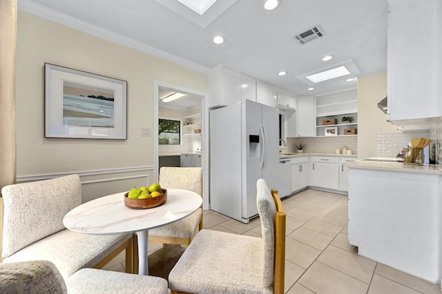 7313 Grover Ave, Austin, TX 78757 - dining area with a skylight, light tile patterned flooring, ornamental molding, and recessed lighting
