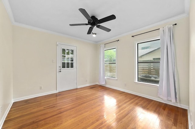 empty room with a ceiling fan, baseboards, crown molding, and wood finished floors