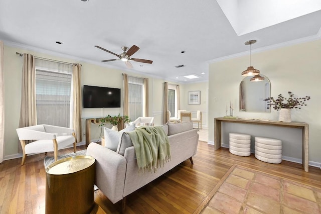 living area featuring ceiling fan, ornamental molding, wood finished floors, and visible vents