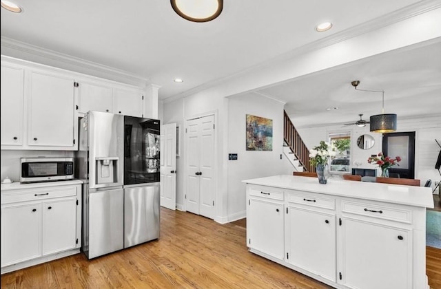 1606 W 14th St, Austin, TX 78703 - kitchen with appliances with stainless steel finishes, light wood-style flooring, white cabinetry, ornamental molding, and light countertops