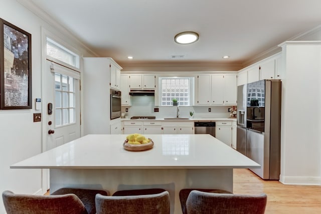 1606 W 14th St, Austin, TX 78703 - kitchen with stainless steel appliances, under cabinet range hood, light countertops, a breakfast bar, and crown molding