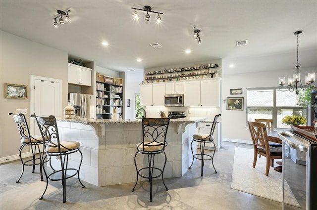 19908 Victoria Chase Rd, Lago Vista, TX 78645 - kitchen with stainless steel appliances, finished concrete floors, a kitchen breakfast bar, a chandelier, and light stone countertops