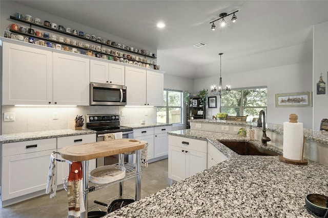 19908 Victoria Chase Rd, Lago Vista, TX 78645 - kitchen featuring stainless steel appliances, concrete floors, tasteful backsplash, a chandelier, and white cabinets