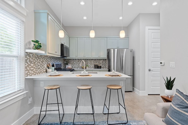 kitchen with appliances with stainless steel finishes, a sink, a peninsula, decorative backsplash, and recessed lighting