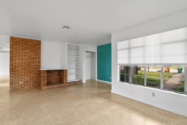 unfurnished living room featuring speckled floor, built in shelves, brick wall, baseboards, and visible vents