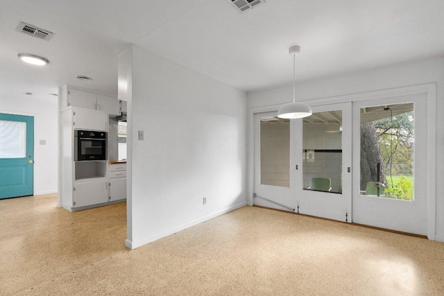 unfurnished dining area featuring baseboards, visible vents, and light speckled floor