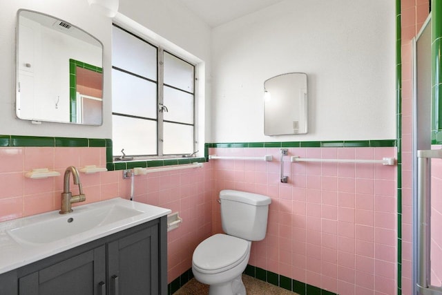 bathroom featuring tile walls, a wainscoted wall, vanity, and toilet
