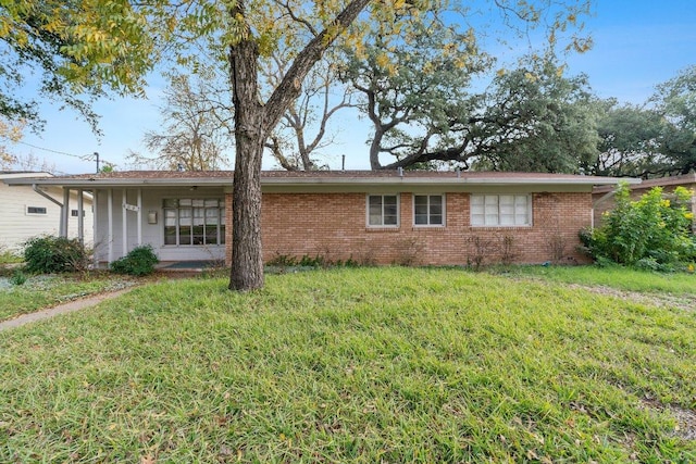 rear view of house featuring a lawn and brick siding