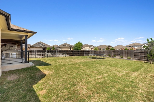 view of yard featuring a fenced backyard, a residential view, and a trampoline