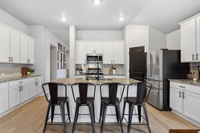 kitchen with white cabinetry, appliances with stainless steel finishes, a breakfast bar area, and decorative backsplash