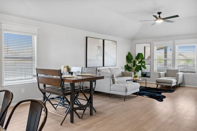living room featuring light wood-type flooring, lofted ceiling, baseboards, and a ceiling fan