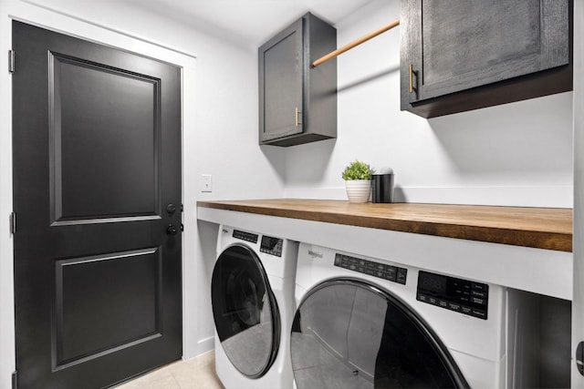laundry room with cabinet space, light tile patterned floors, and washer and clothes dryer