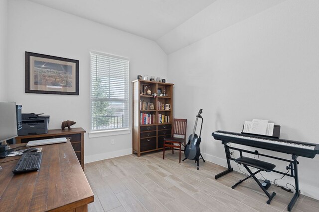 office area featuring vaulted ceiling, light wood-type flooring, and baseboards
