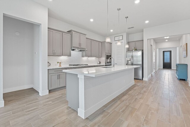 kitchen with light wood-style flooring, stainless steel refrigerator with ice dispenser, a sink, and gray cabinetry