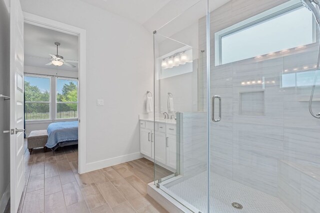 ensuite bathroom featuring baseboards, a wealth of natural light, a ceiling fan, and a stall shower